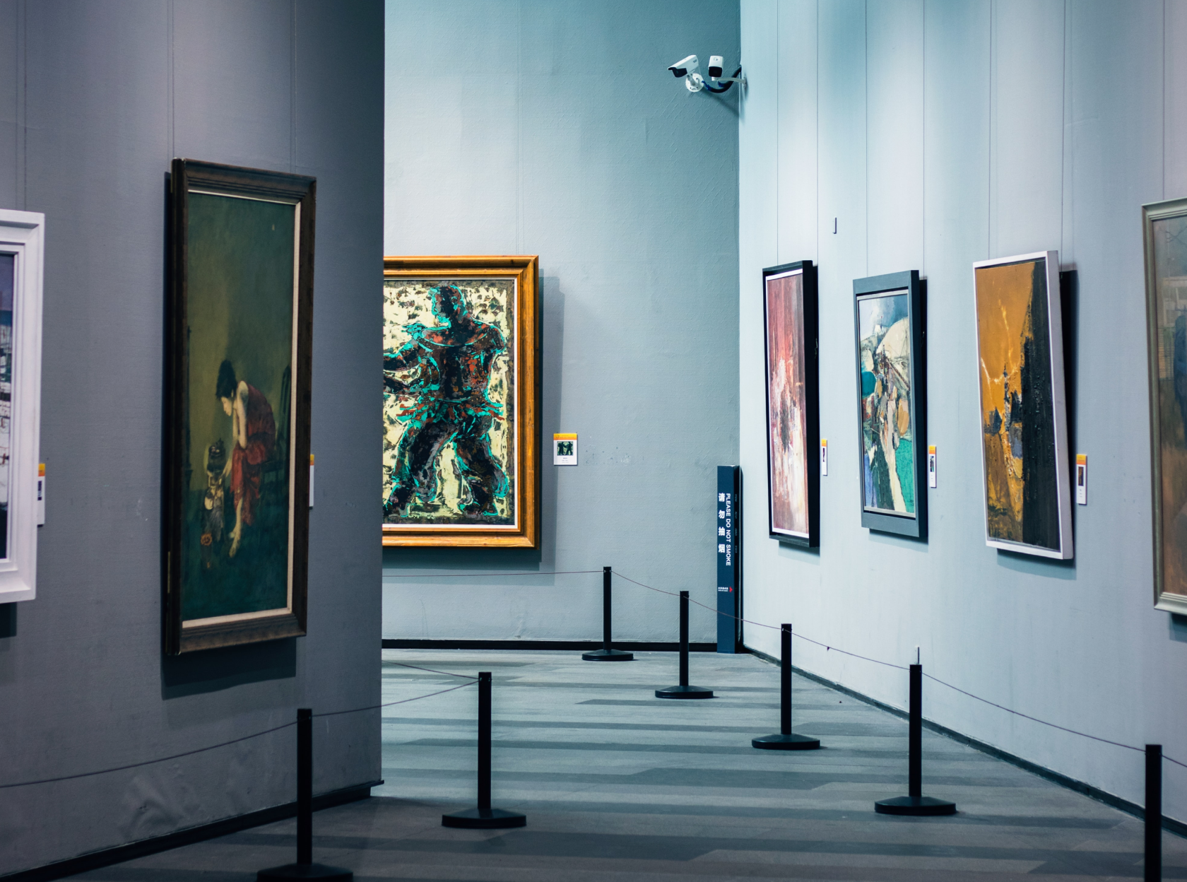 Art gallery interior with framed paintings on grey walls, representing collectible alternative assets