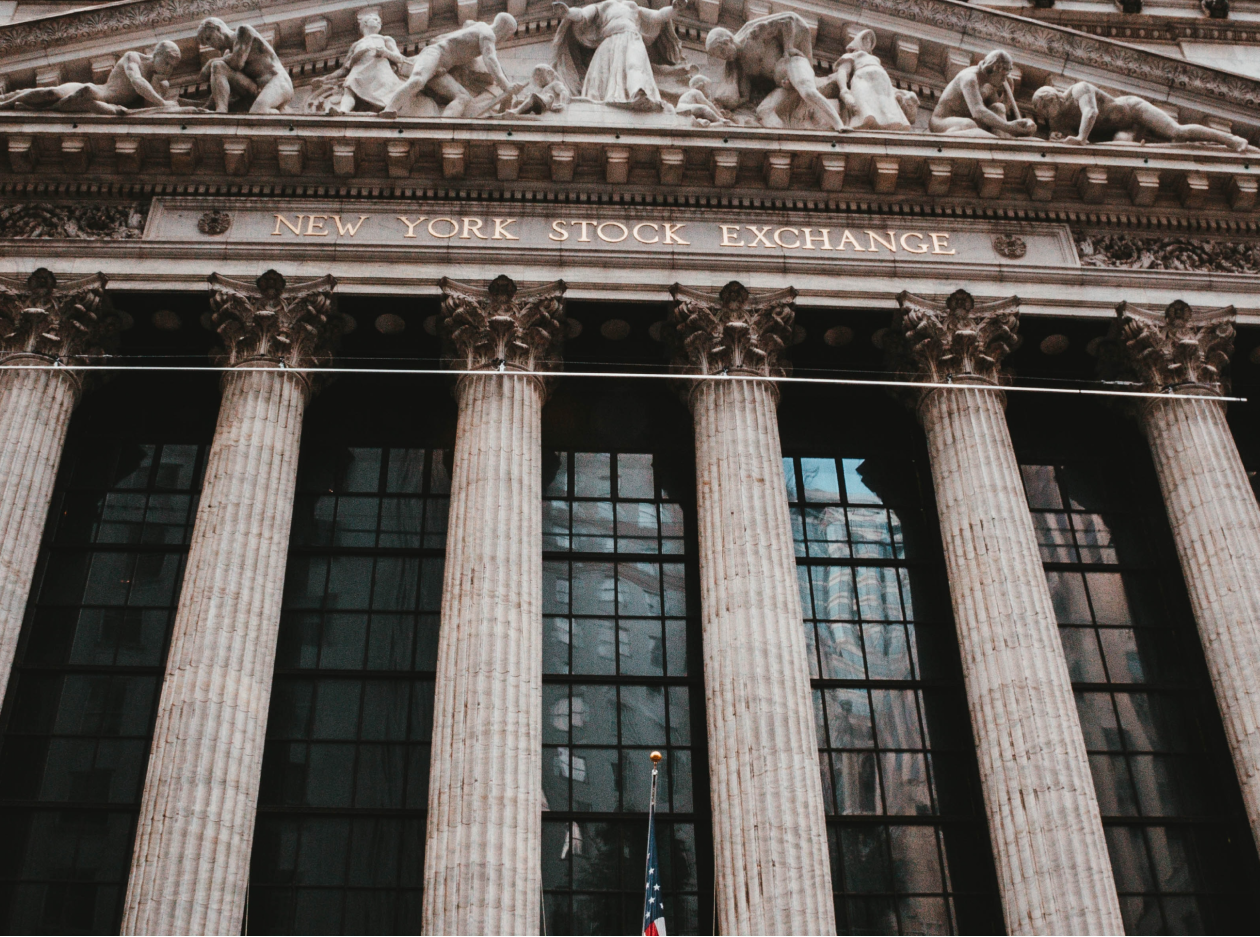 The New York Stock Exchange building facade with classical columns, representing traditional public markets