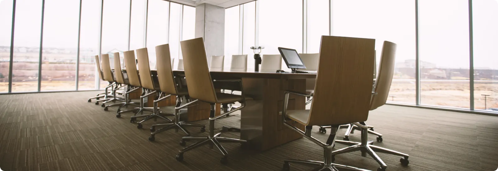 Corporate boardroom with conference table and chairs overlooking a landscape through floor-to-ceiling windows