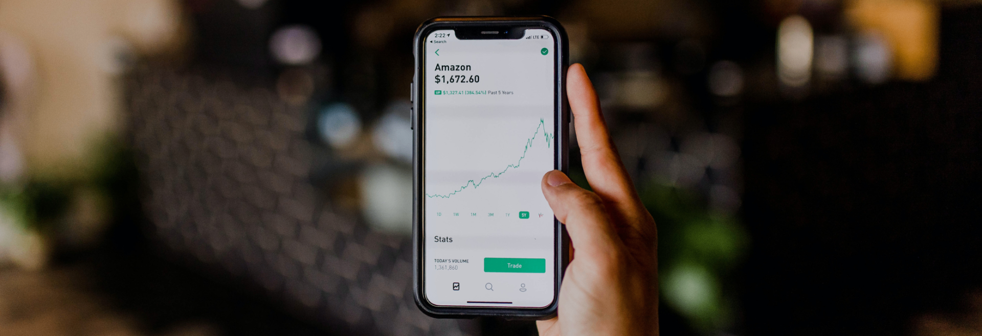 Hand holding smartphone showing stock chart performance